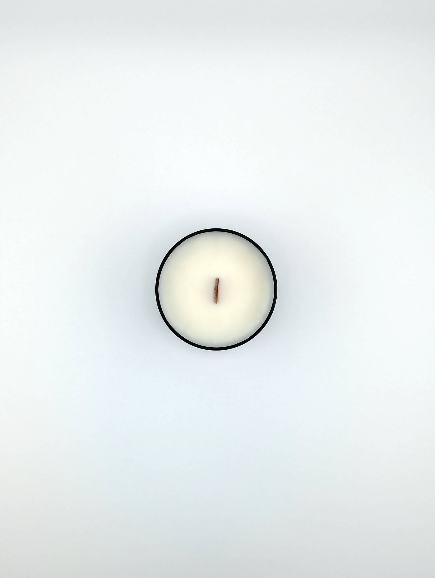 Small white candle in a round container on a light gray background