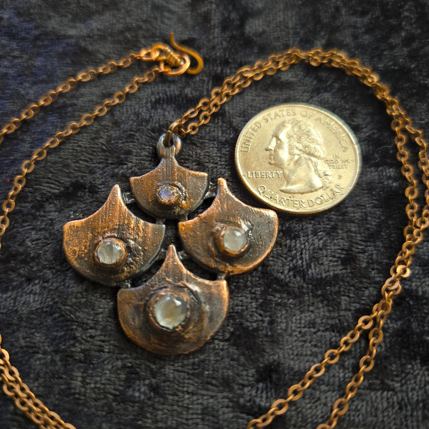 Copper necklace with a unique design on a dark textured fabric background