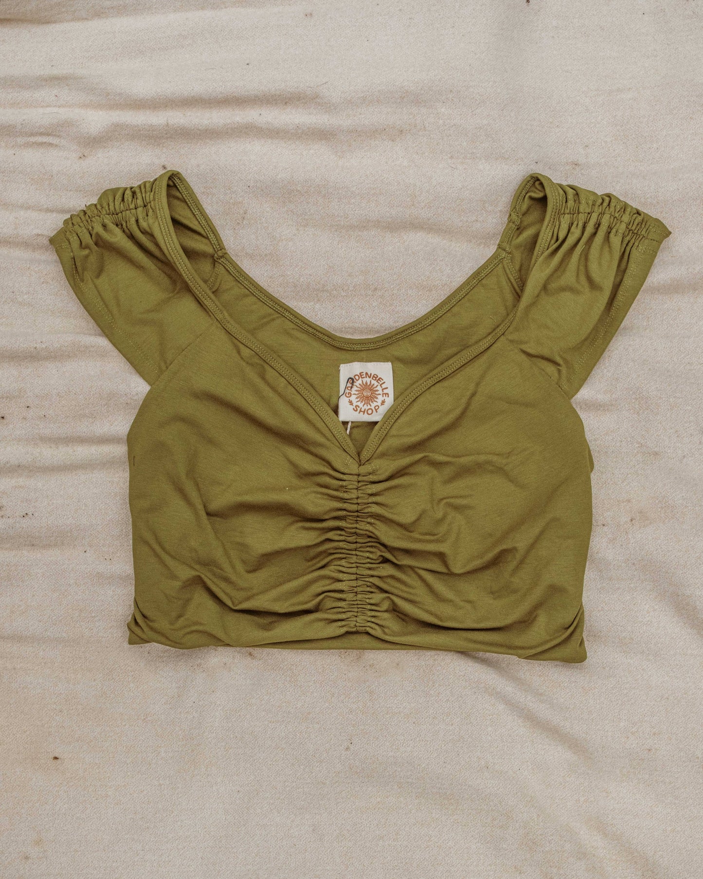 Green crop top with a brand label on a beige surface