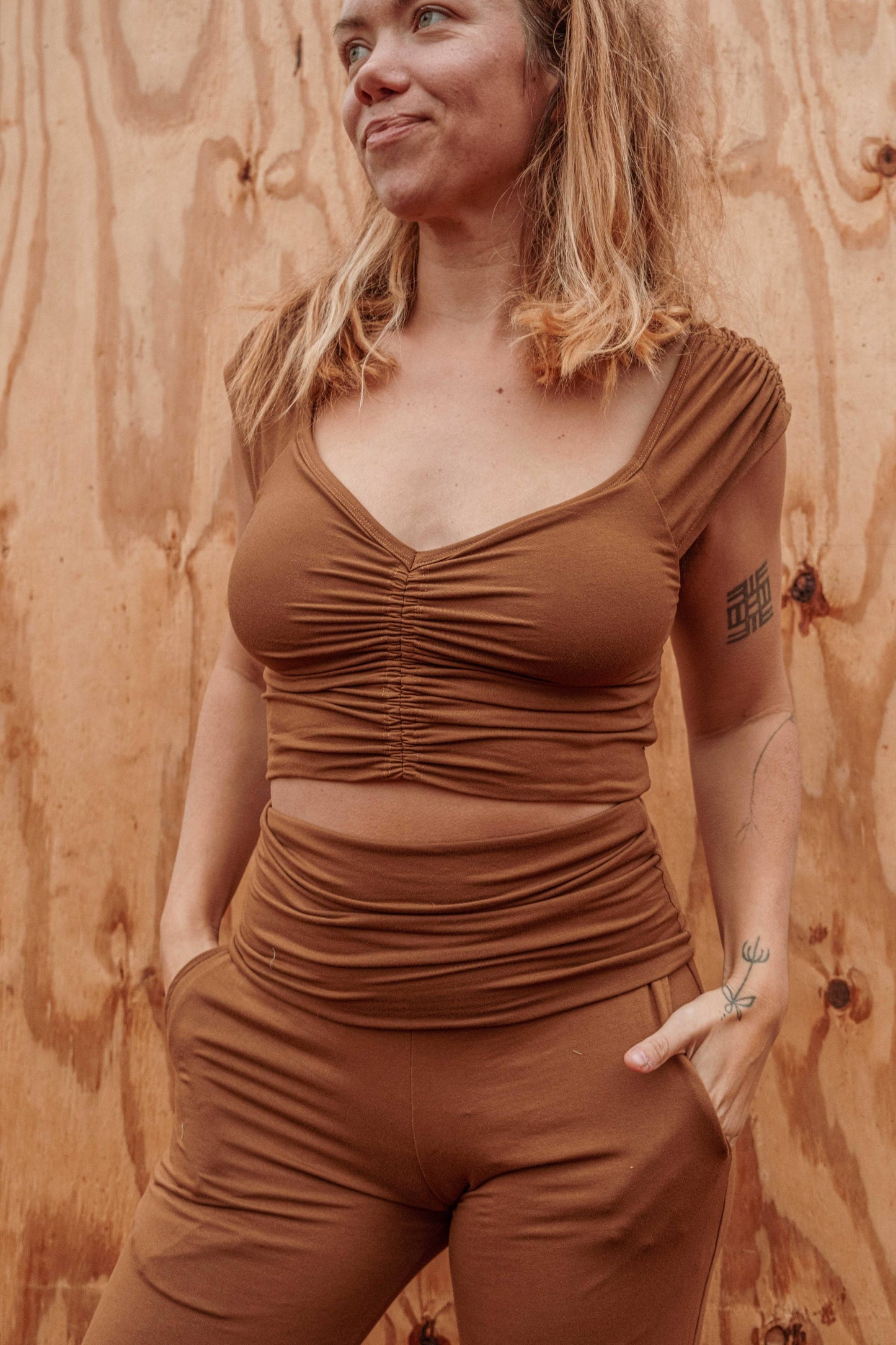 Woman wearing a brown ruched top and shorts against a wooden background