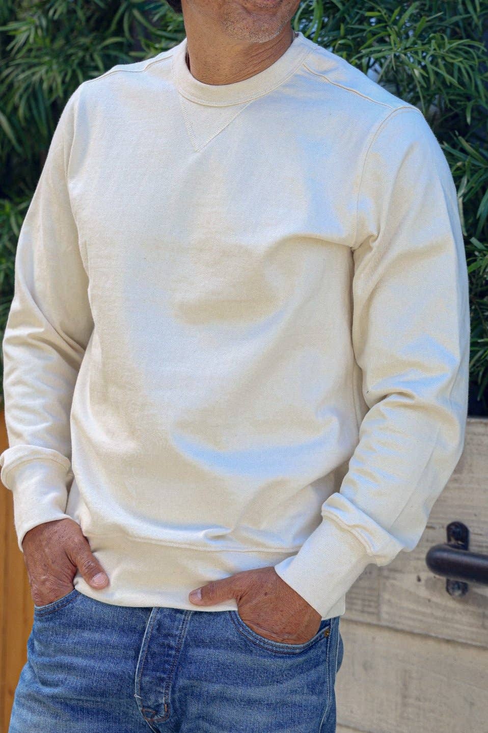 Person wearing a cream-colored sweatshirt with blue accents outdoors.