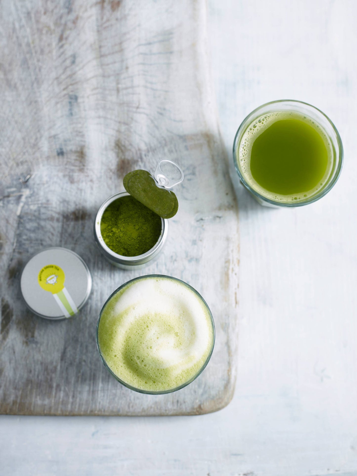 Two glasses of green juice on a wooden board with a light background