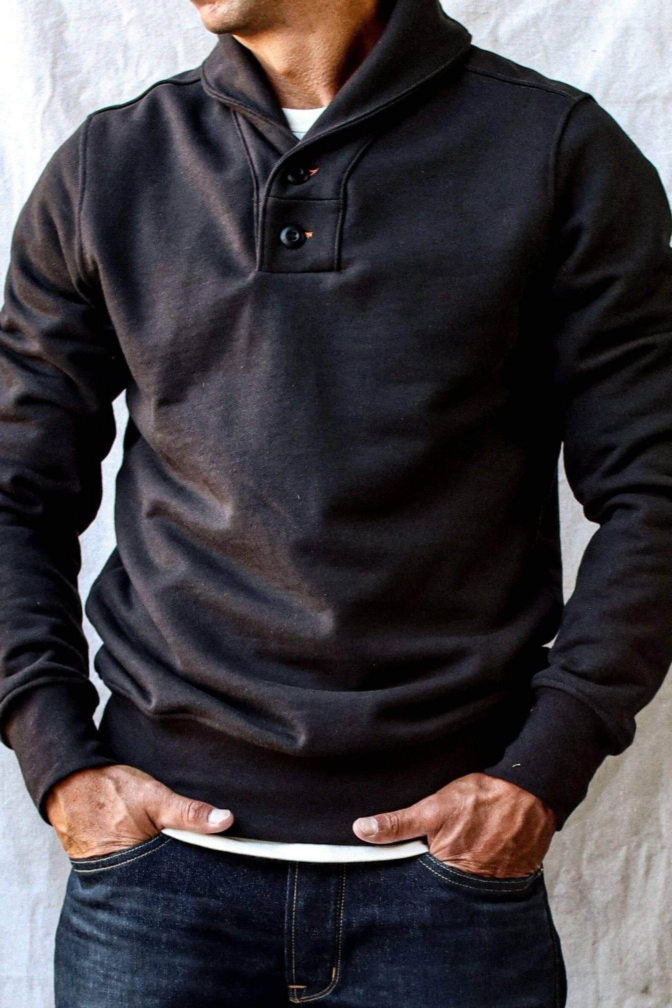Person wearing a black long-sleeve shirt with a collar against a neutral background