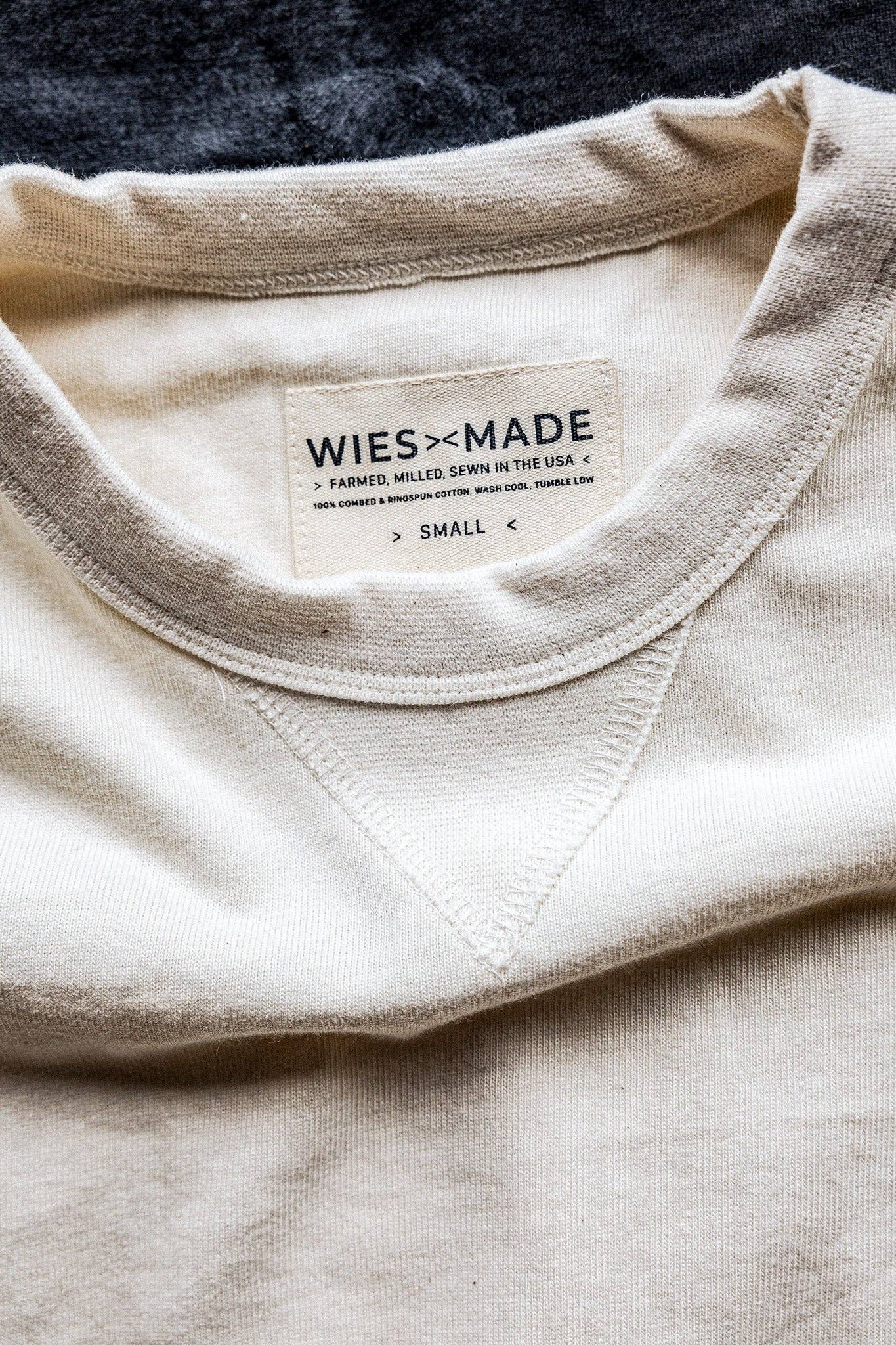 Close-up of a beige shirt with a 'WiesMade' label on a dark background