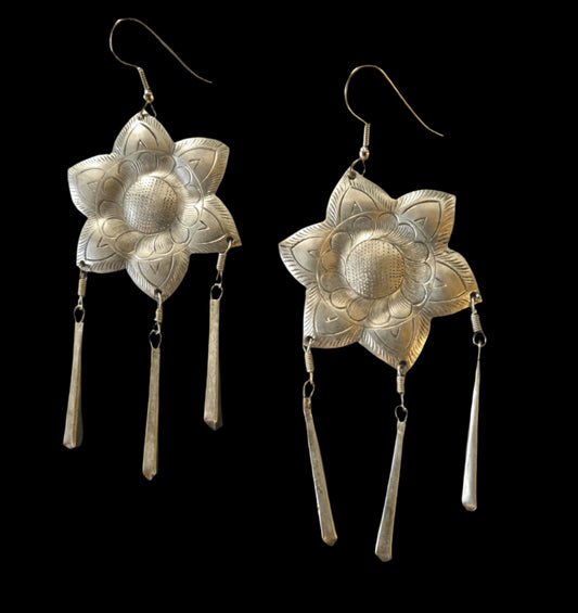Pair of Indian silver flower-shaped earrings with dangling elements on a dark background
